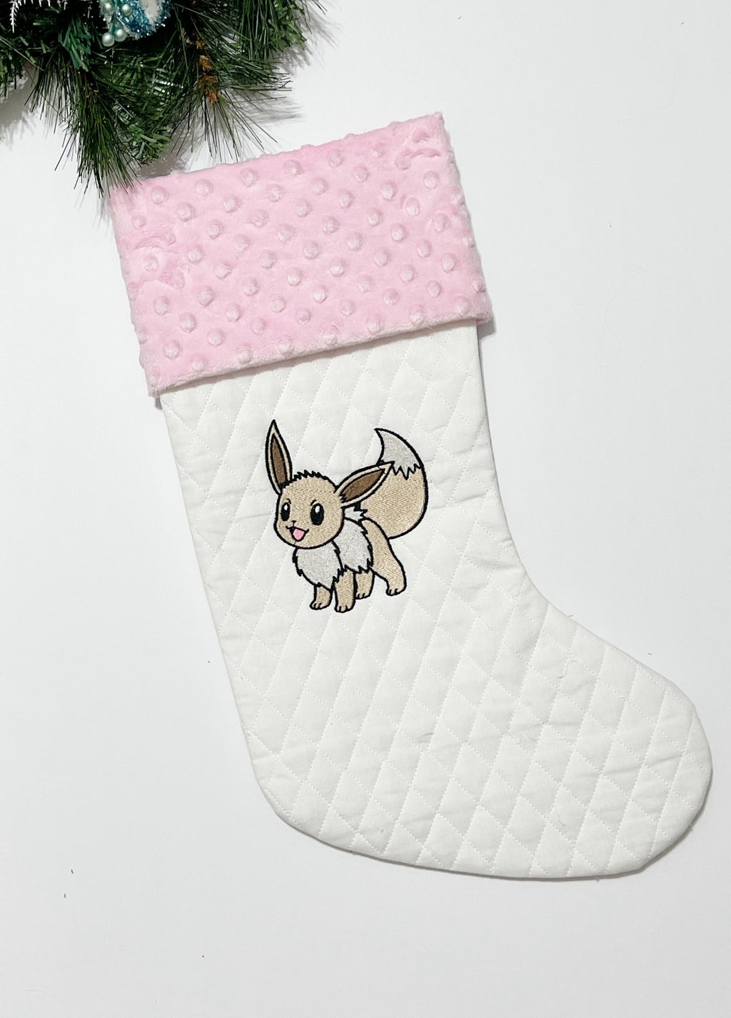 Personalized Christmas stocking made from white quilted fabric featuring embroidered Eevee evolution on front, fully lined, and minky cuff