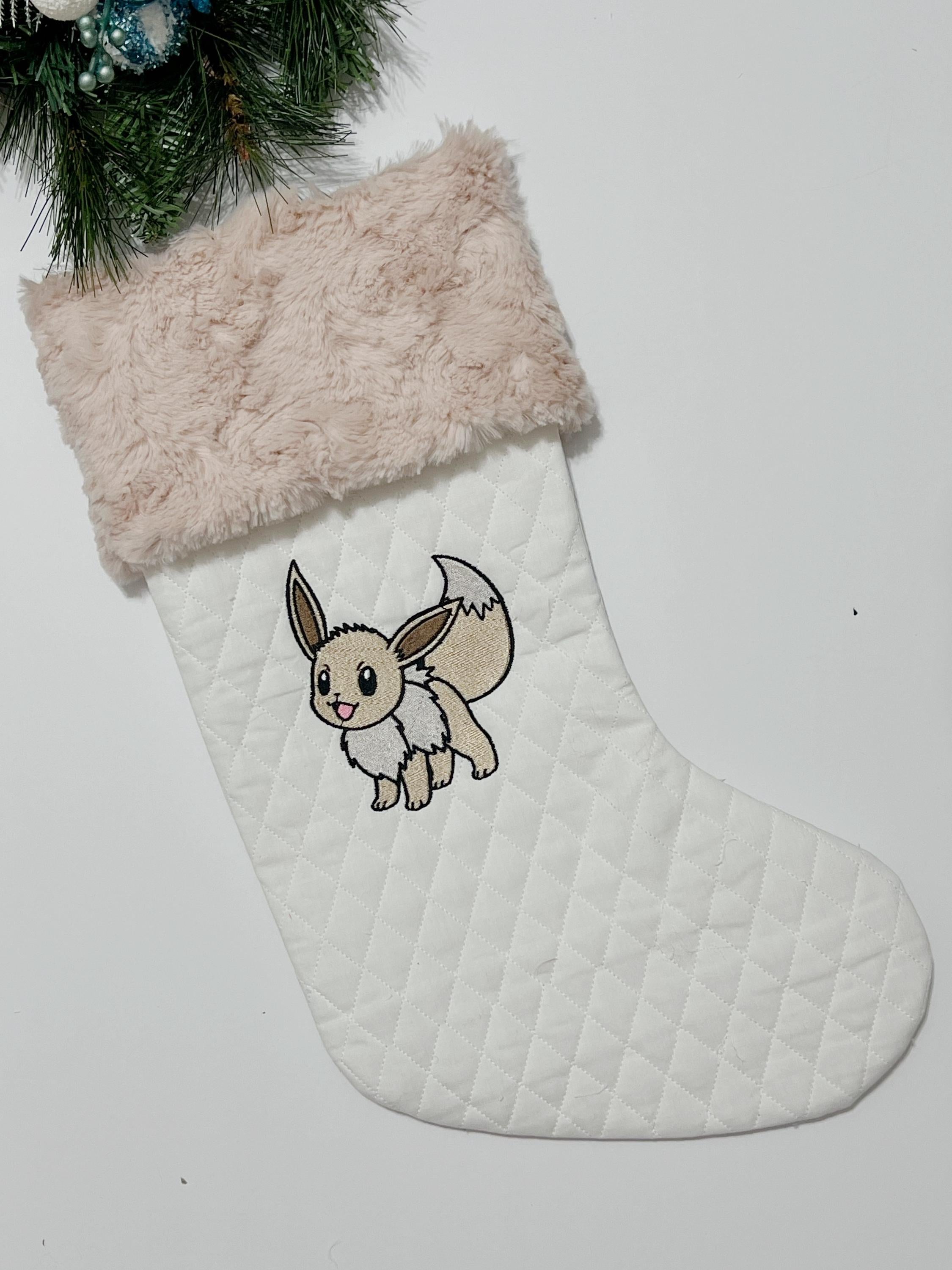 Personalized Christmas stocking made from white quilted fabric featuring embroidered Eevee evolution on front, fully lined, and minky cuff